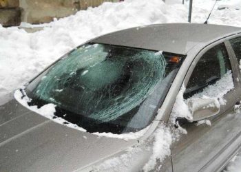 Oštećen automobil parkiran pored zgrade nakon što je led pao sa krova tokom zime.
